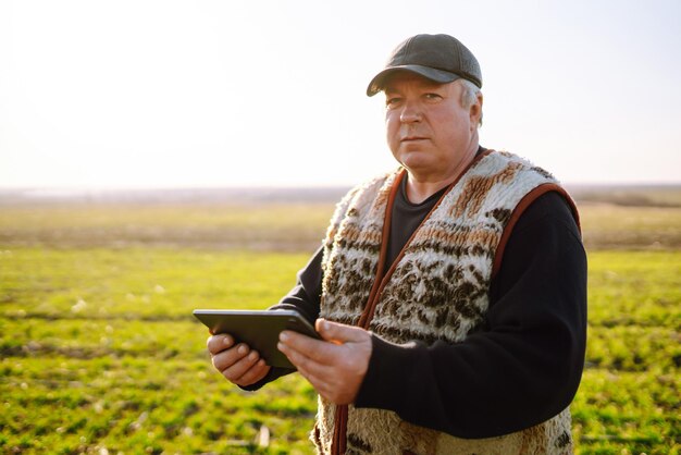 Boer op een tarweveld met een tablet in zijn handen bij zonsondergang Slimme boerderij Landbouw tuinieren