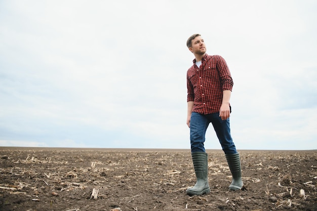 Boer staat in een geploegd veld Landbouw gewas concept