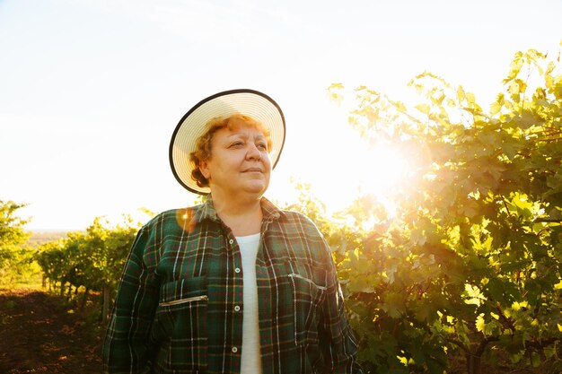 Boer vrouw wijnmaker portret van een oudere vrouw met hoed op haar hoofd staat op het veld vi...