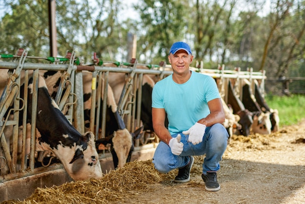 Boer werkt op de boerderij met melkkoeien.