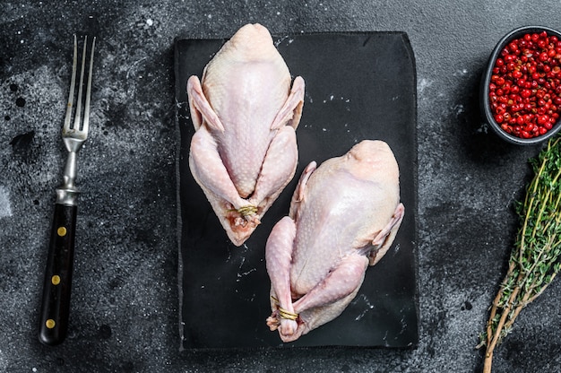 Boerderij eco vriendelijke rauwe kwartels klaar om te koken. Zwarte achtergrond. Bovenaanzicht.