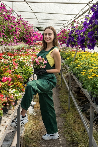 Foto boerin werkt in een tuincentrum en verzorgt haar verschillende bloemen. lente