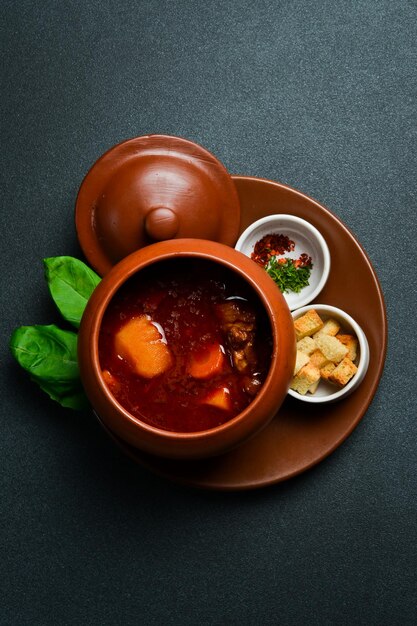 Photo bograch with meat and vegetables in a clay bowl free space for text close up