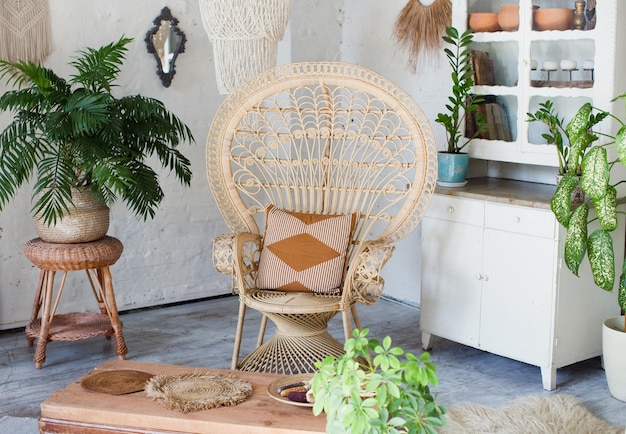 Boheems stijlvol interieur met pauw fauteuil groene planten in bloempotten en vintage boho details