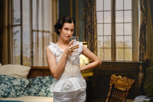 Bohemian life Actrice in vintage pyjama in slaapkamer met een glas droge witte wijn in de hand