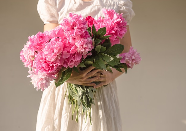 Boho girl holding pink peonies in hands.