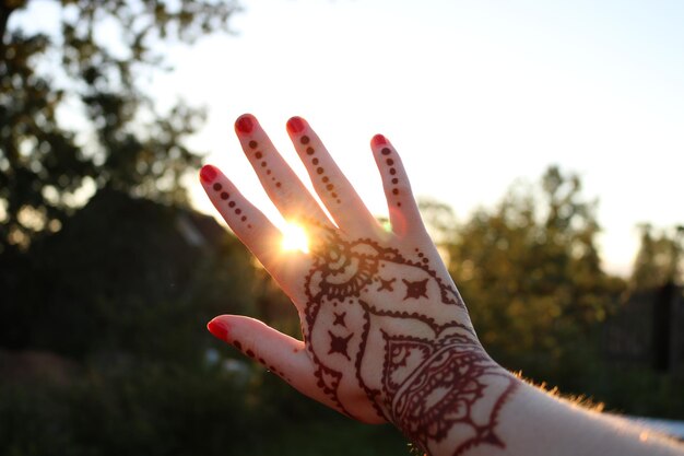 Boho hand on the background of the magical happy sun with mehendi. Brown henna. Natural picture.