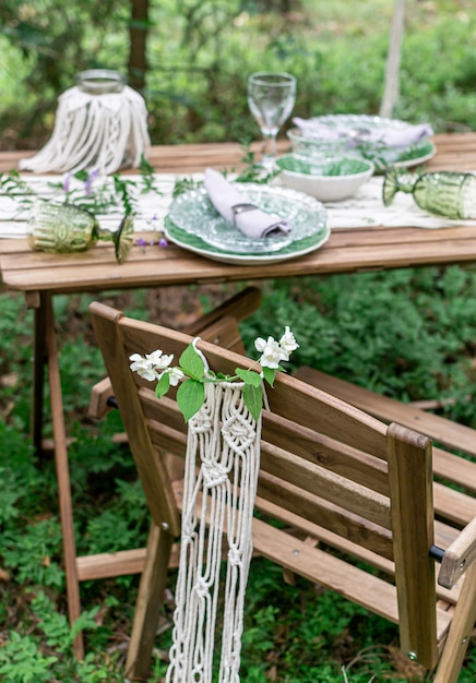 Boho stijl bruiloft receptie eettafel met macrame tafelkleed, decoratie op een rustieke houten tafel