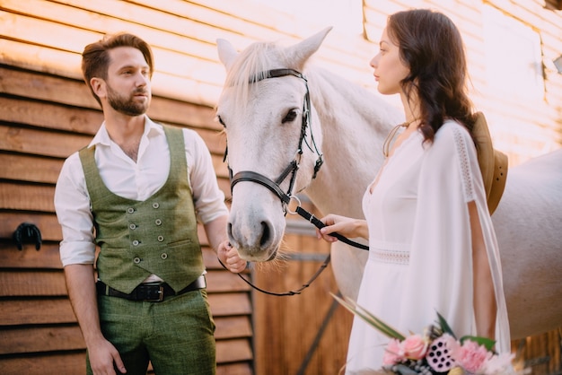 Boho style newlyweds standing near horse, close up