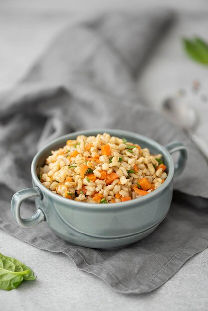 Photo boiled barley porridge with vegetables and spices in a gray plate closeup