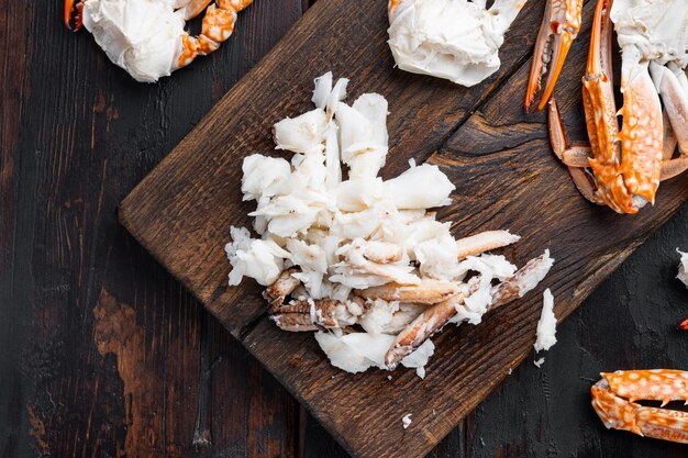 Boiled blue swimming crab claws set, on wooden cutting board, on dark wooden background, top view flat lay