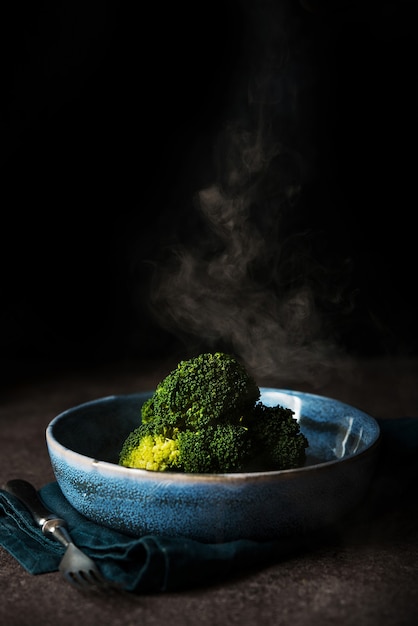 Boiled broccoli with a steam a plate on a black background with a copy of space