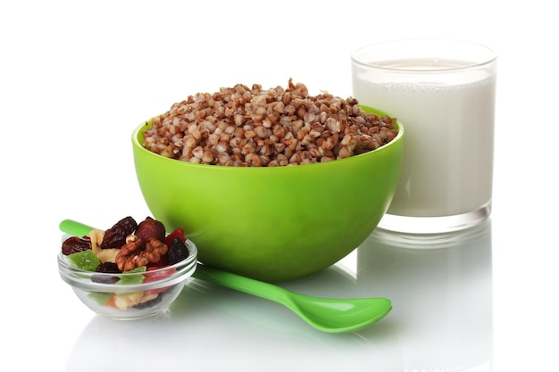 Boiled buckwheat in a green bowl a glass of milk isolated on white