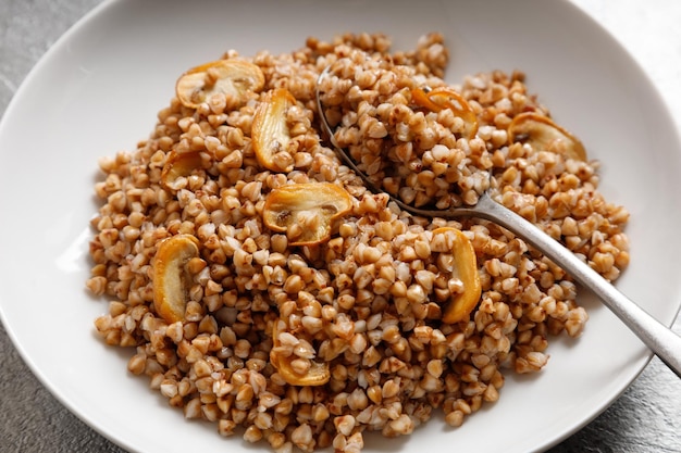 Boiled buckwheat porridge with mushrooms with a spoon on the plate