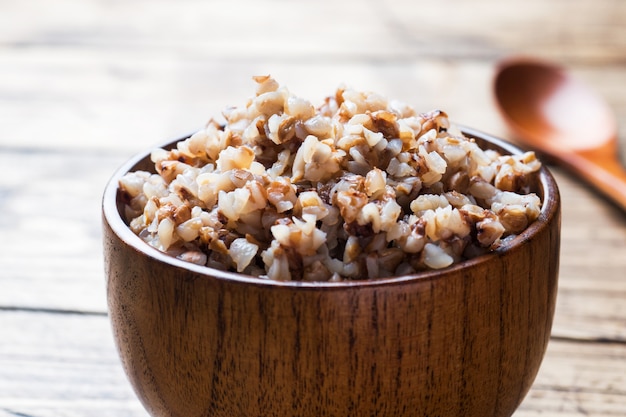 Boiled buckwheat in a wooden bowl on the village table.