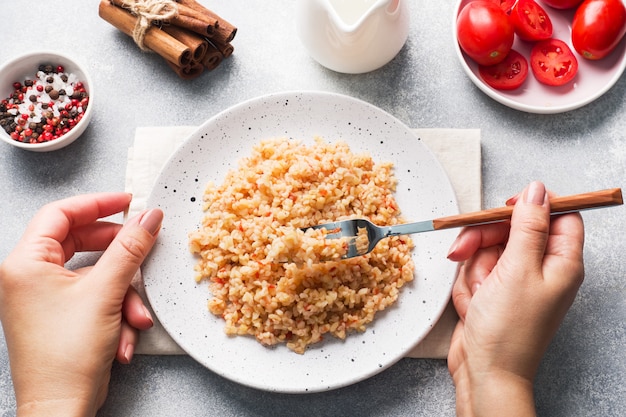 Boiled bulgur with tomatoes in a ceramic plate.