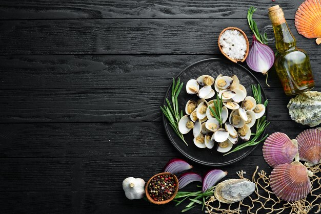 Vongole bollite con spezie in un piatto frutti di mare su sfondo nero vista dall'alto spazio libero per la copia