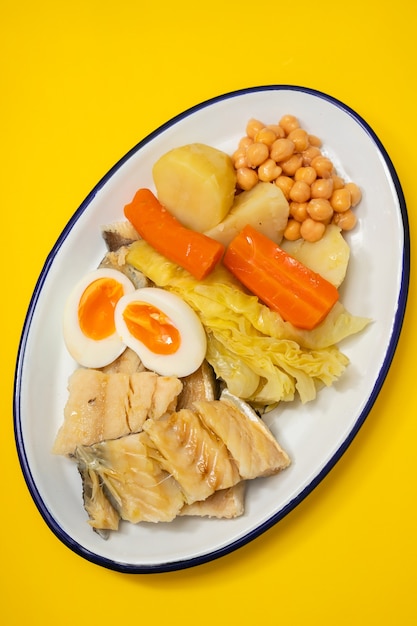 흰 접시에 삶은 야채와 계란 삶은 대구 생선