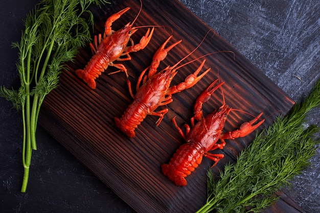 Boiled cooked crayfish crawfish ready to eat on dark wooden background. Copy space. Overhead.