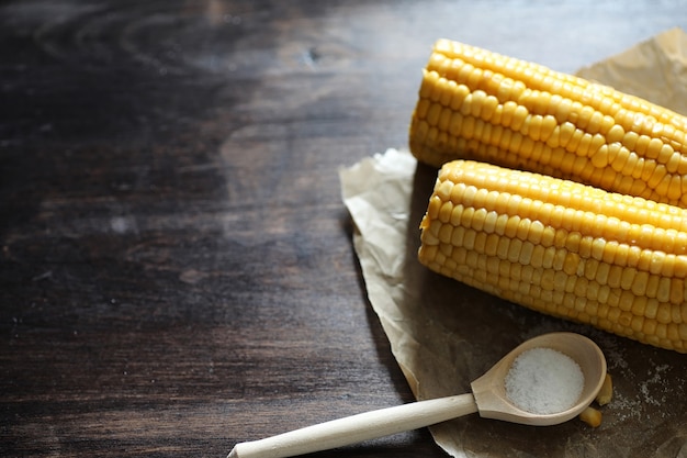 Boiled corn cob with salt on a wooden table