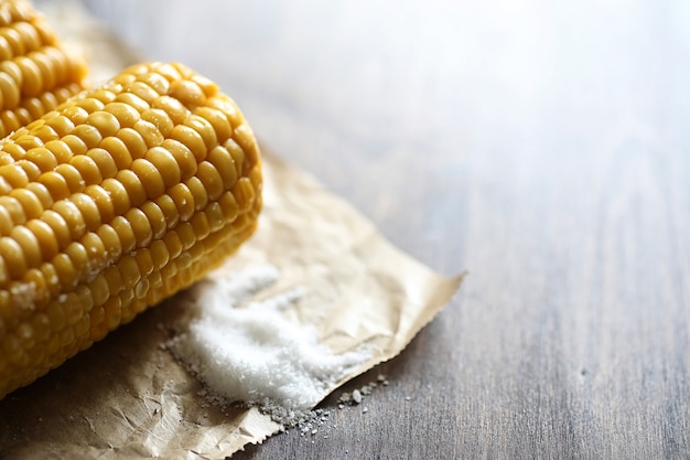 Boiled corn cob with salt on a wooden table