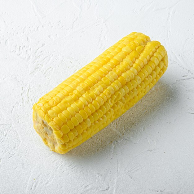 Boiled corn slices set, on white stone  table, square format