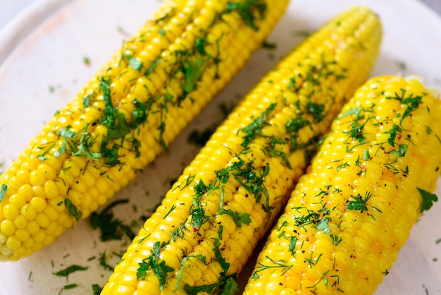 Boiled corn with spices on grey light concrete background. Copy space