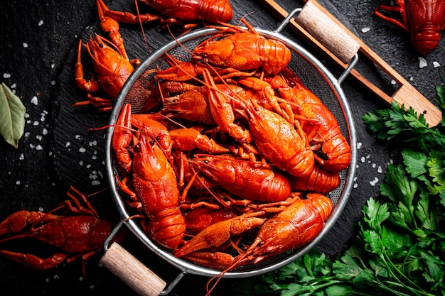 Boiled crayfish in a colander on a stone board