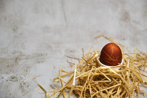 Вареное пасхальное яйцо в держателе на соломенном гнезде