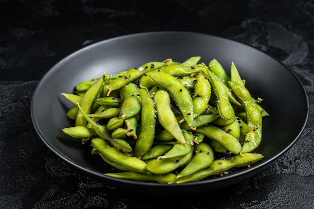 Boiled Edamame Soy Beans with sea salt in a plate Black background Top view