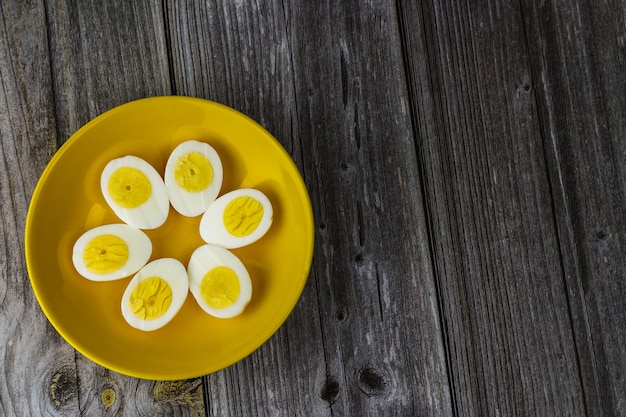 Photo boiled egg halves in a yellow bowl on wooden table