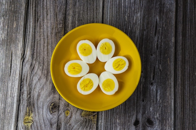 Photo boiled egg halves in a yellow bowl on wooden table