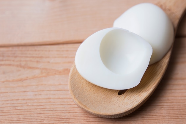 boiled egg peeling on wooden spoon 