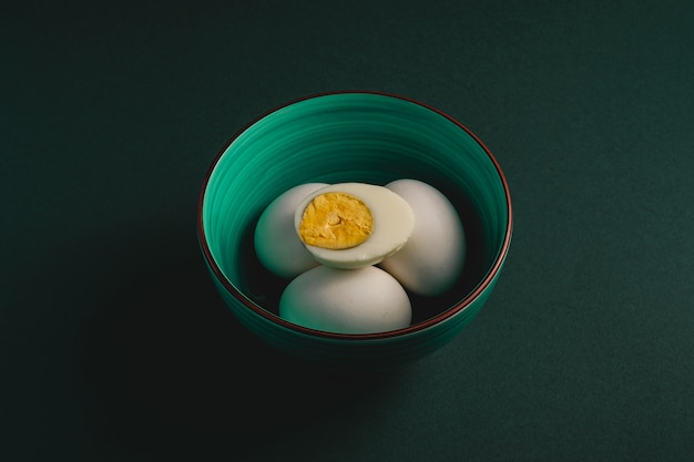 Boiled egg with yellow yolk with white eggs in green bowl on black