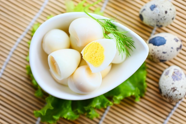 Boiled eggs food quail eggs on white bowl breakfast eggs with fresh quail eggs and vegetable lettuce on table background top view