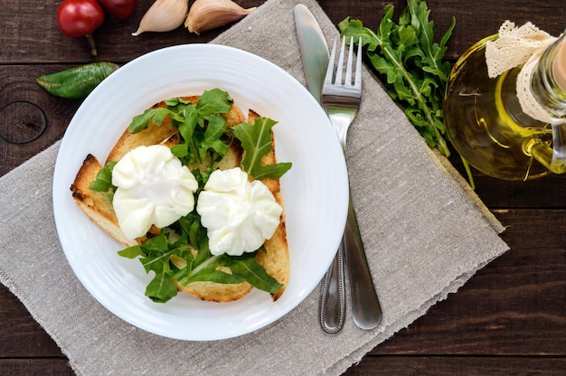 Boiled eggs in a pouch poached on crispy toast and green arugula leaves