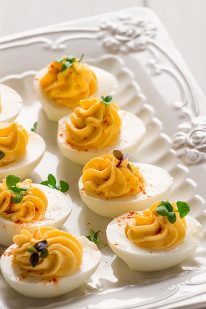 Вареные яйца, фаршированные желтком с майонезом на белой тарелке, выборочный фокус, размытый крупный план, нет людей