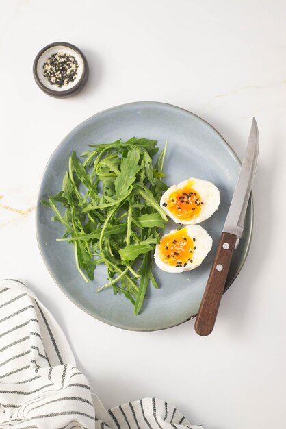 Boiled eggs with arugula on a gray plate on gray background