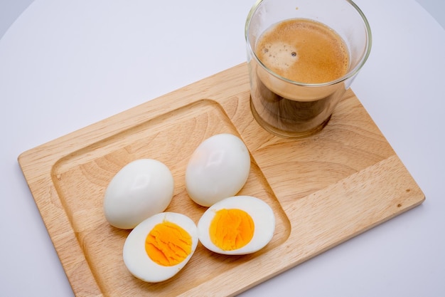 Uova sode con caffè nero su vassoio in legno isolato su sfondo bianco