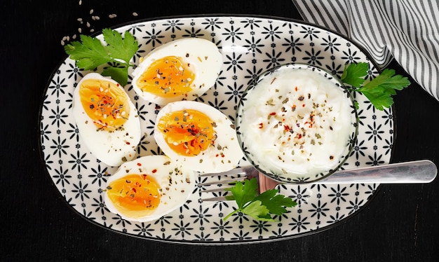 Boiled eggs with yogurt peppers parsley and cup tea Healthy diet food for breakfast Top view flat lay