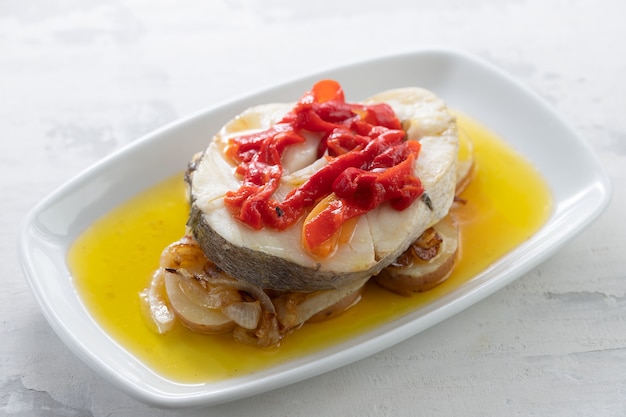 Boiled fish with vegetables, olive oil in dish on ceramic