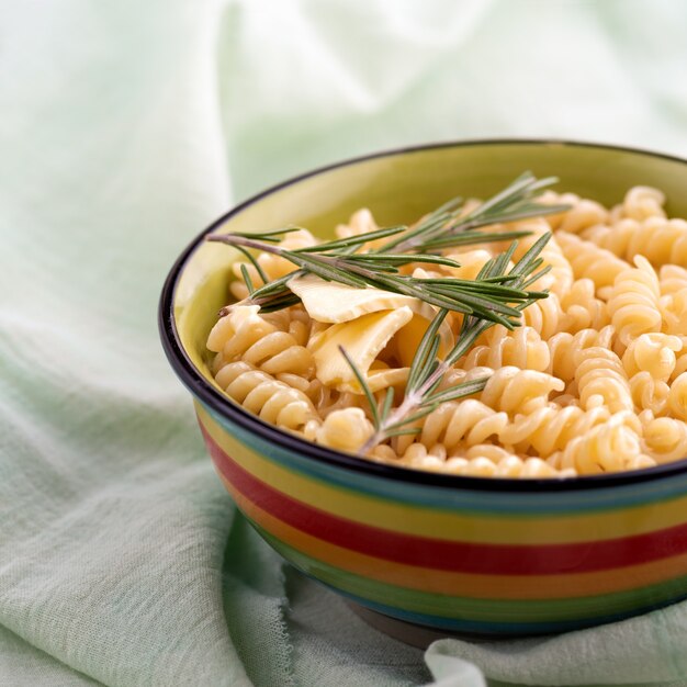 Boiled fusilli pasta with rosemary in a plate a on bright table. close up, the still life, selective focus.