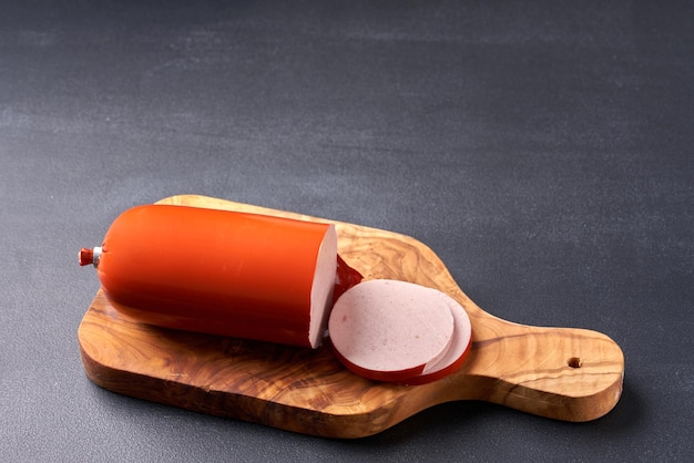 Boiled ham sausage sliced on a wooden kitchen board.