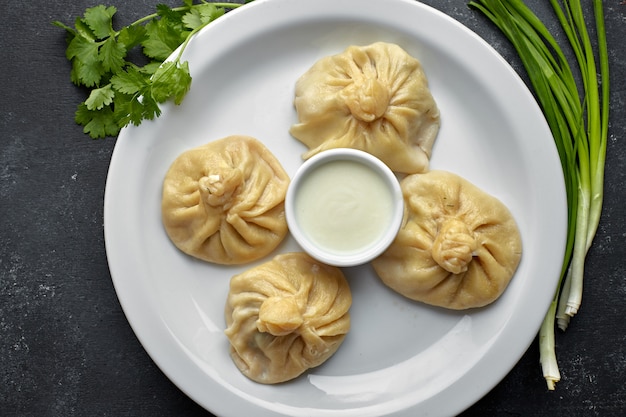 Boiled khinkali with sauce and herbs