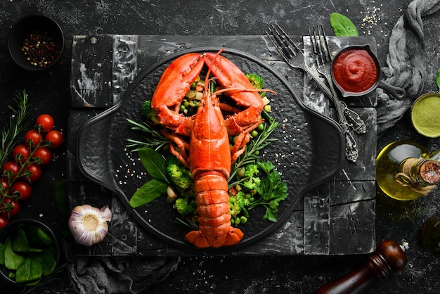 Boiled lobster with vegetables on a black stone plate Seafood Top view Free space for your text