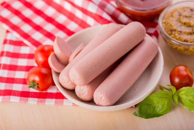 Boiled milk sausages with cherry tomato ketchup and dijon mustard on a wooden table
