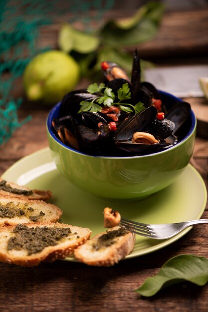 Boiled mussels in cooking dish on wooden background