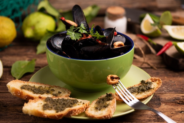 Boiled mussels in cooking dish on wooden background