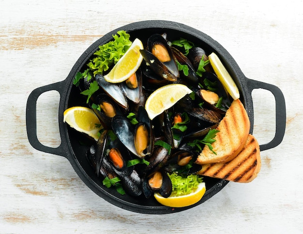 Boiled mussels with garlic parsley and lemon in a frying pan Top view Free space for your text