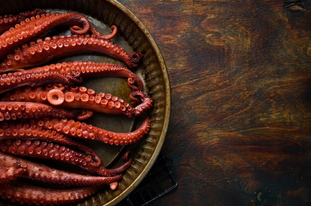 Boiled octopus in a round metal baking dish Seafood Top view Flat lay